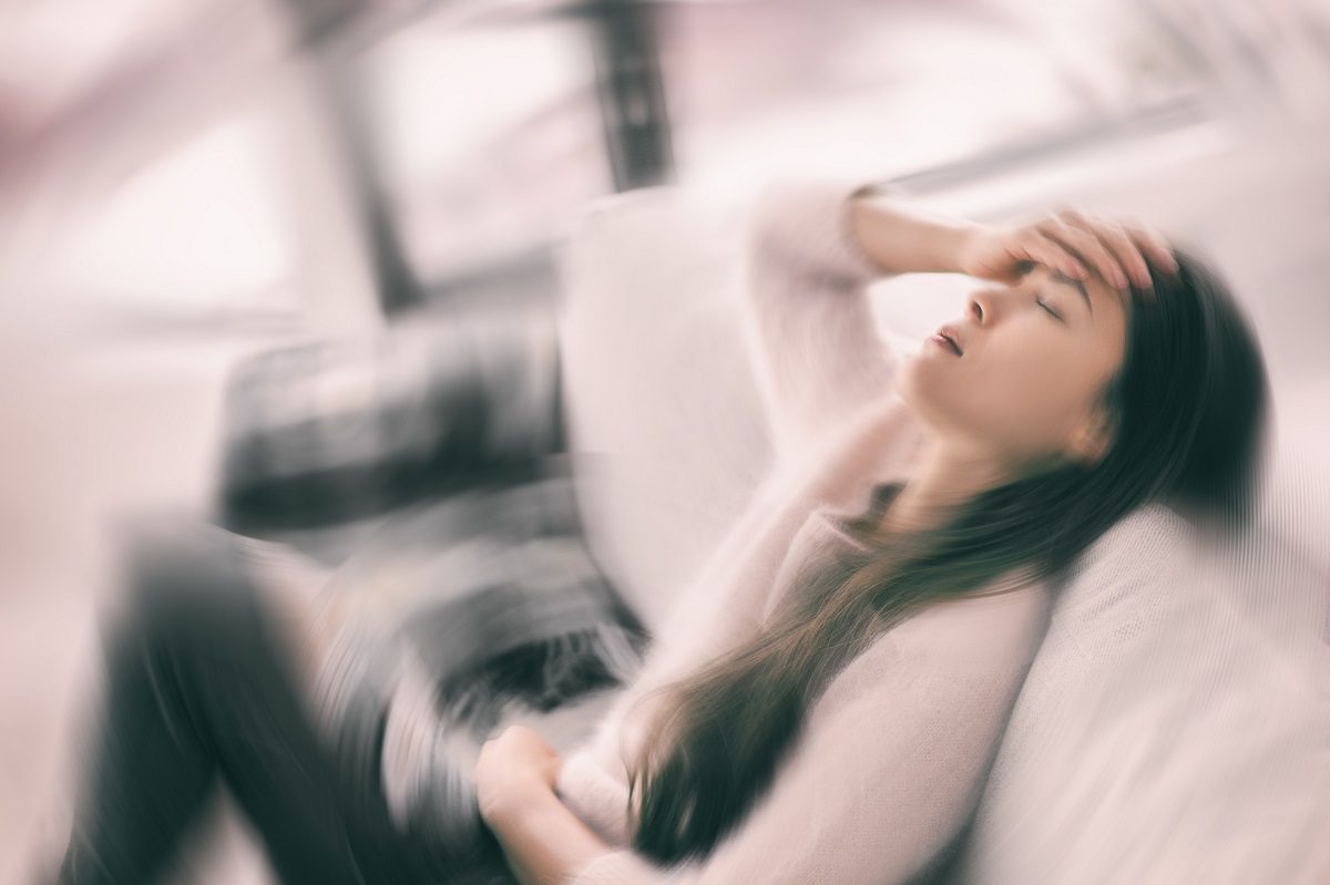 Sick woman with headache holding head, Blurry motion blur background.