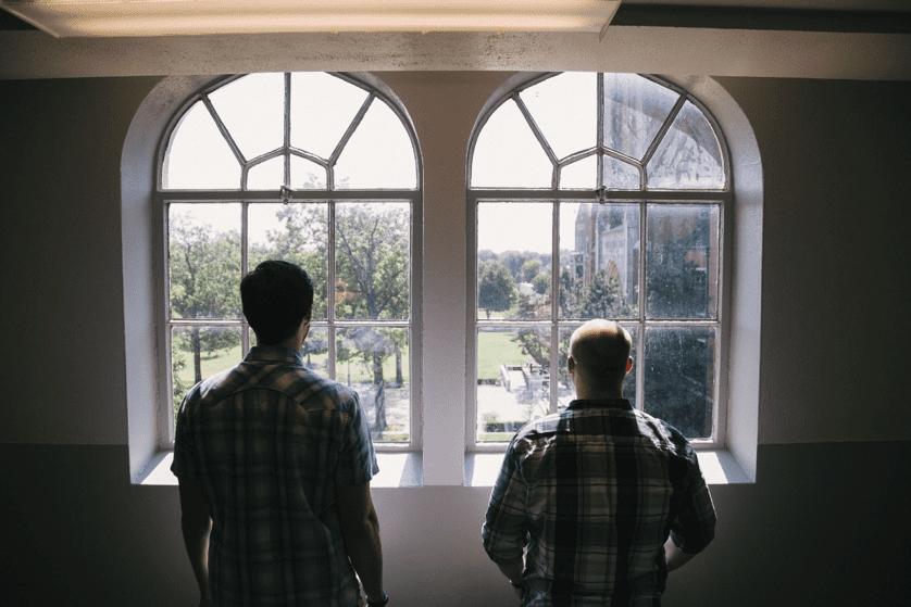 Two men staring out of a window