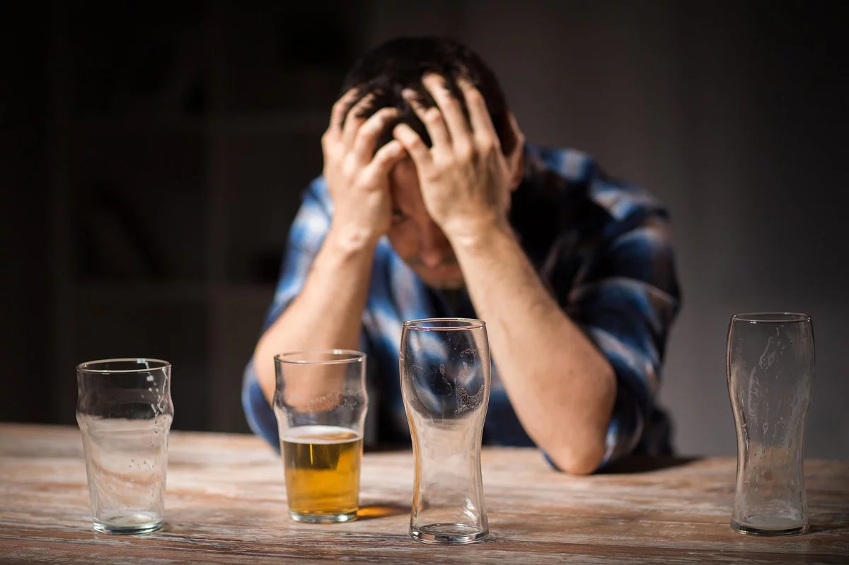 male alcoholic drinking beer from glass at night