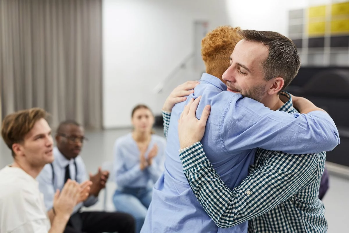 man hugging psychologist during therapy session in support group