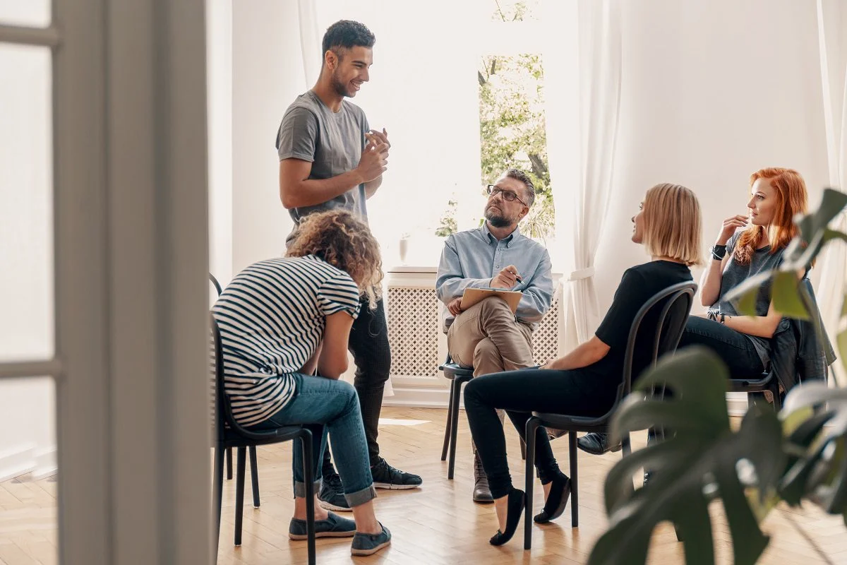 Happy man talking to his support group about his successful fight with drug addiction