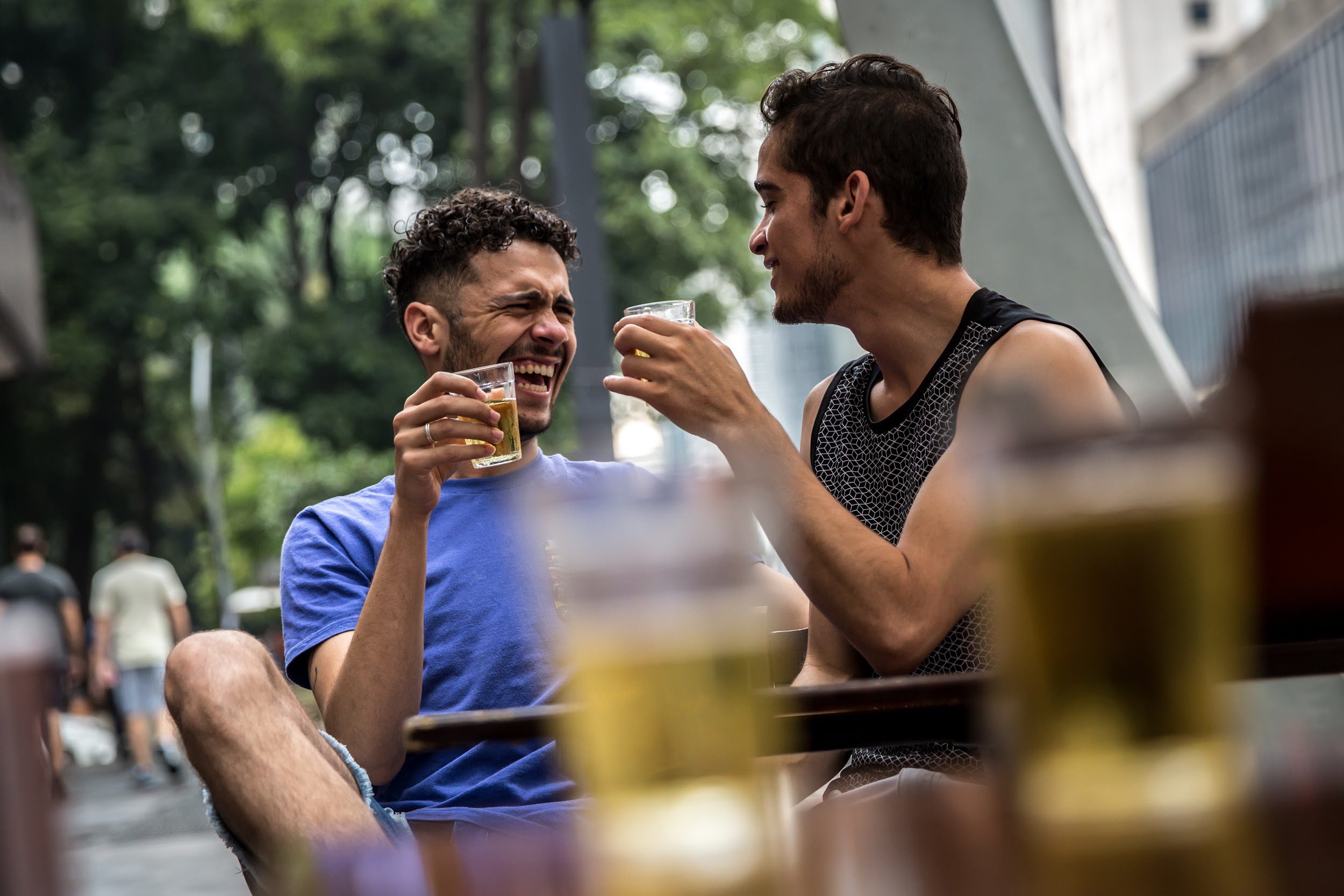 Gay couple drinking beer in street